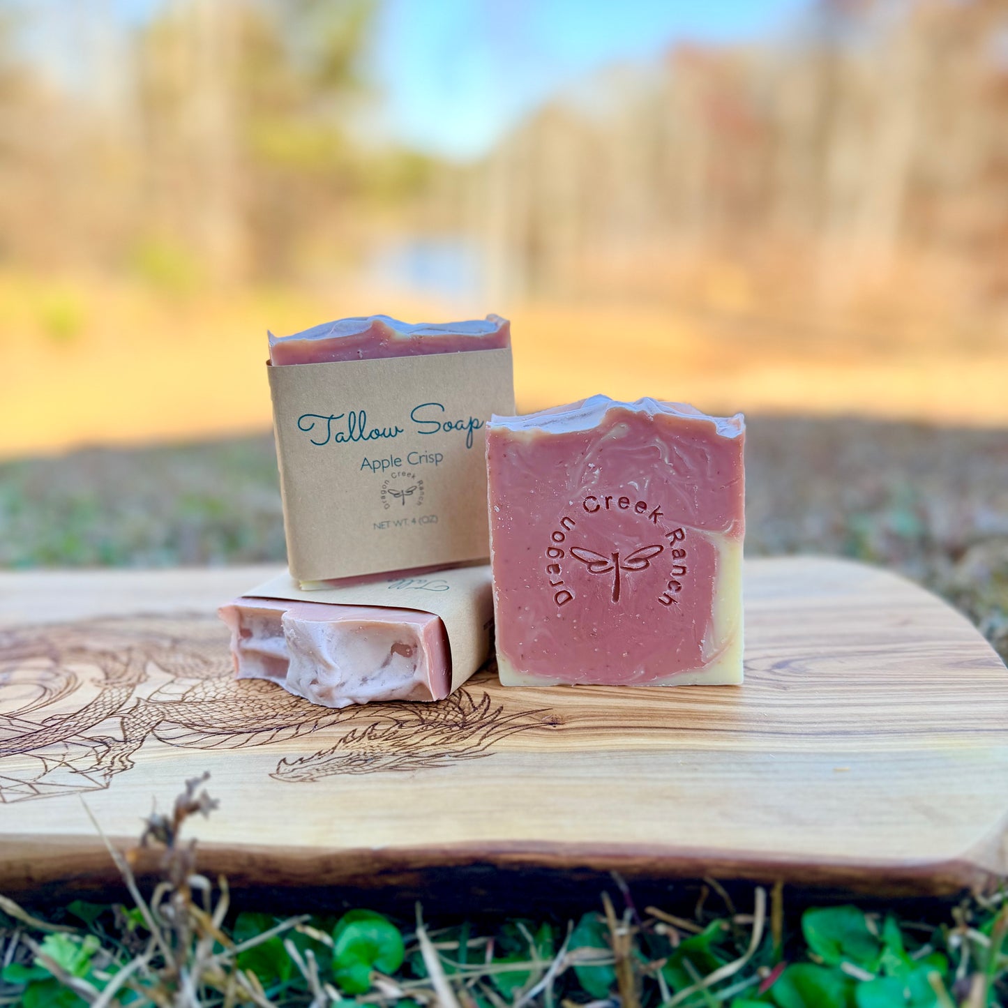 Three bars of pink and cream colored soap on a wooden surface with a natural background