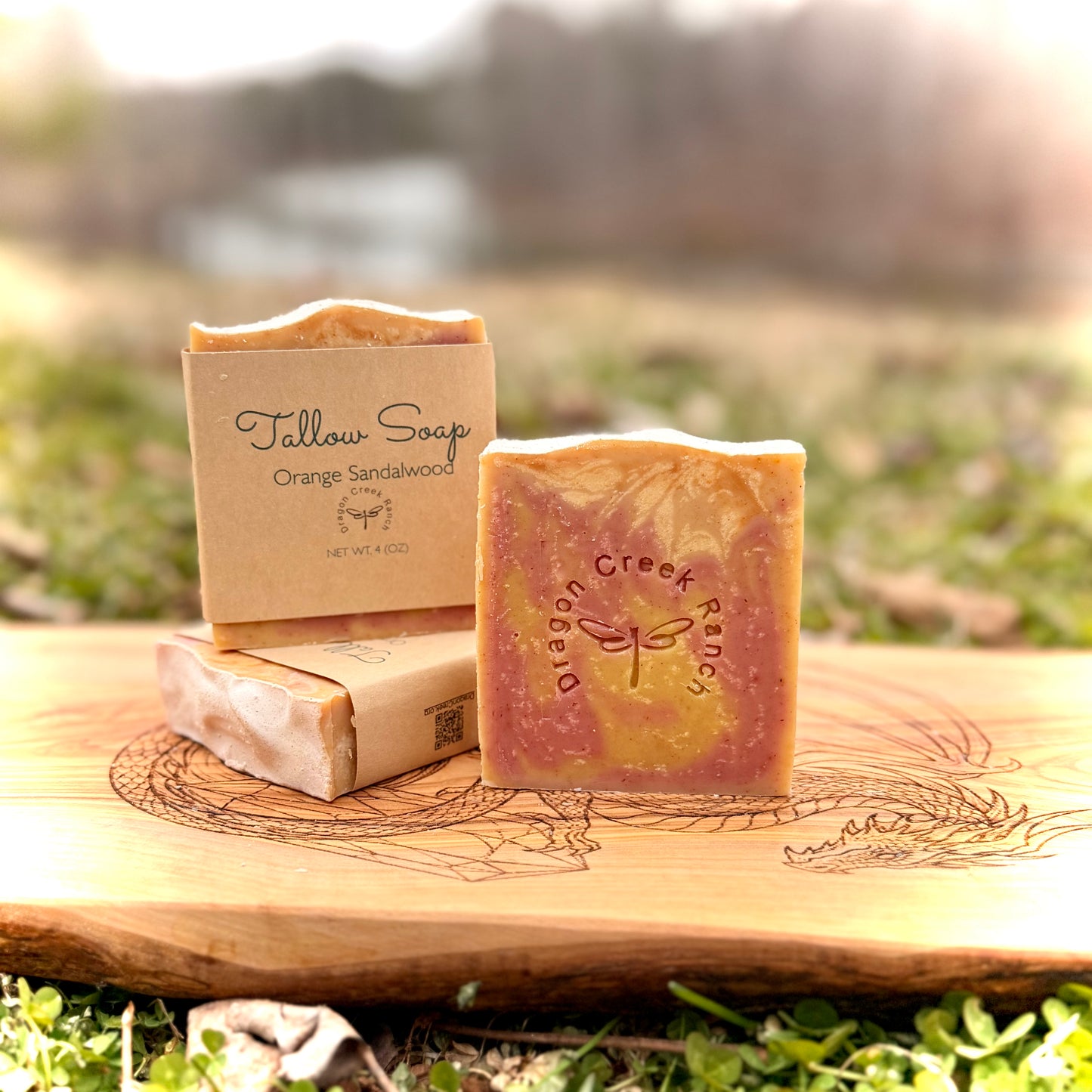 Three bars of soap with visible branding on a wooden surface outdoors.