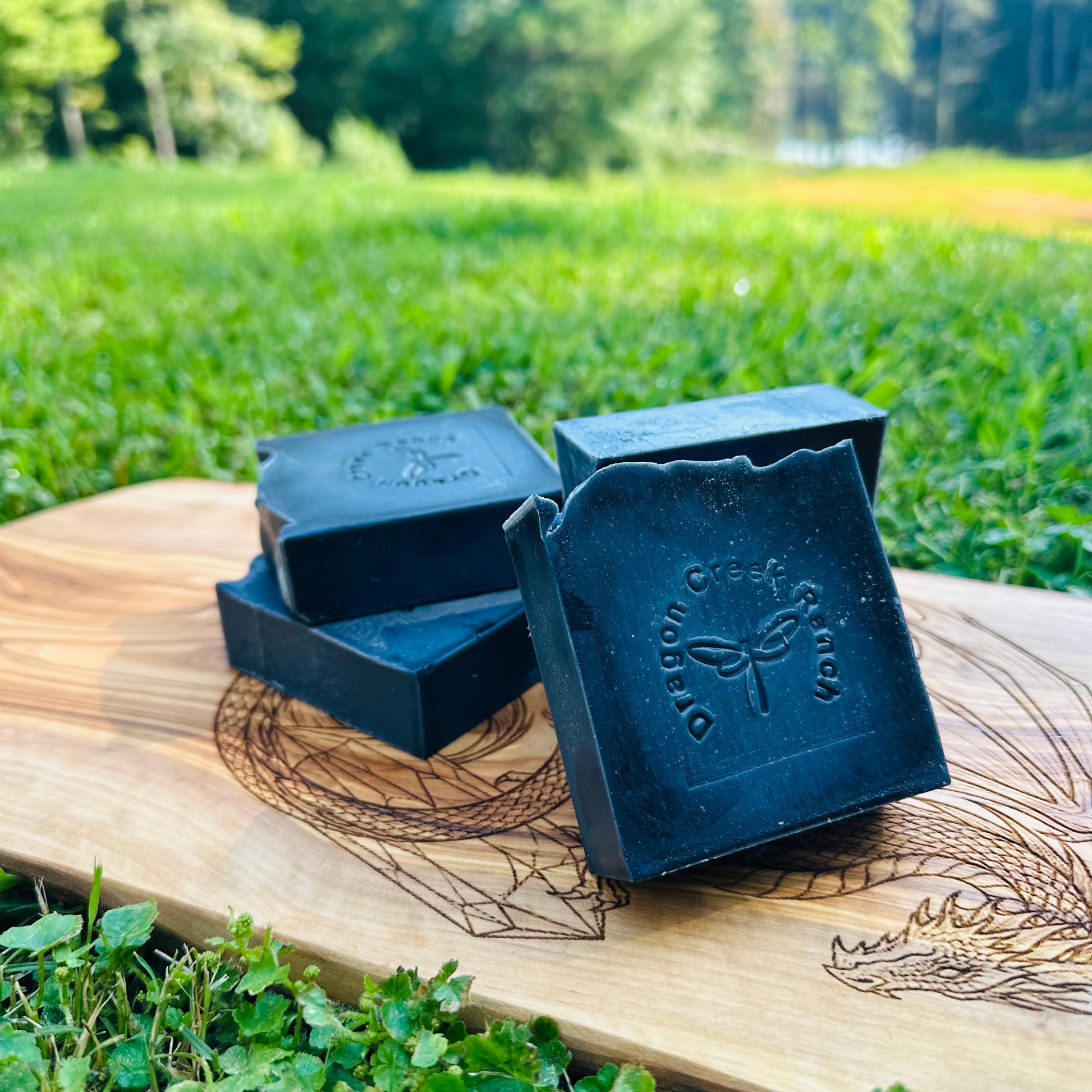 Four black soap bars on a wooden board with a natural background