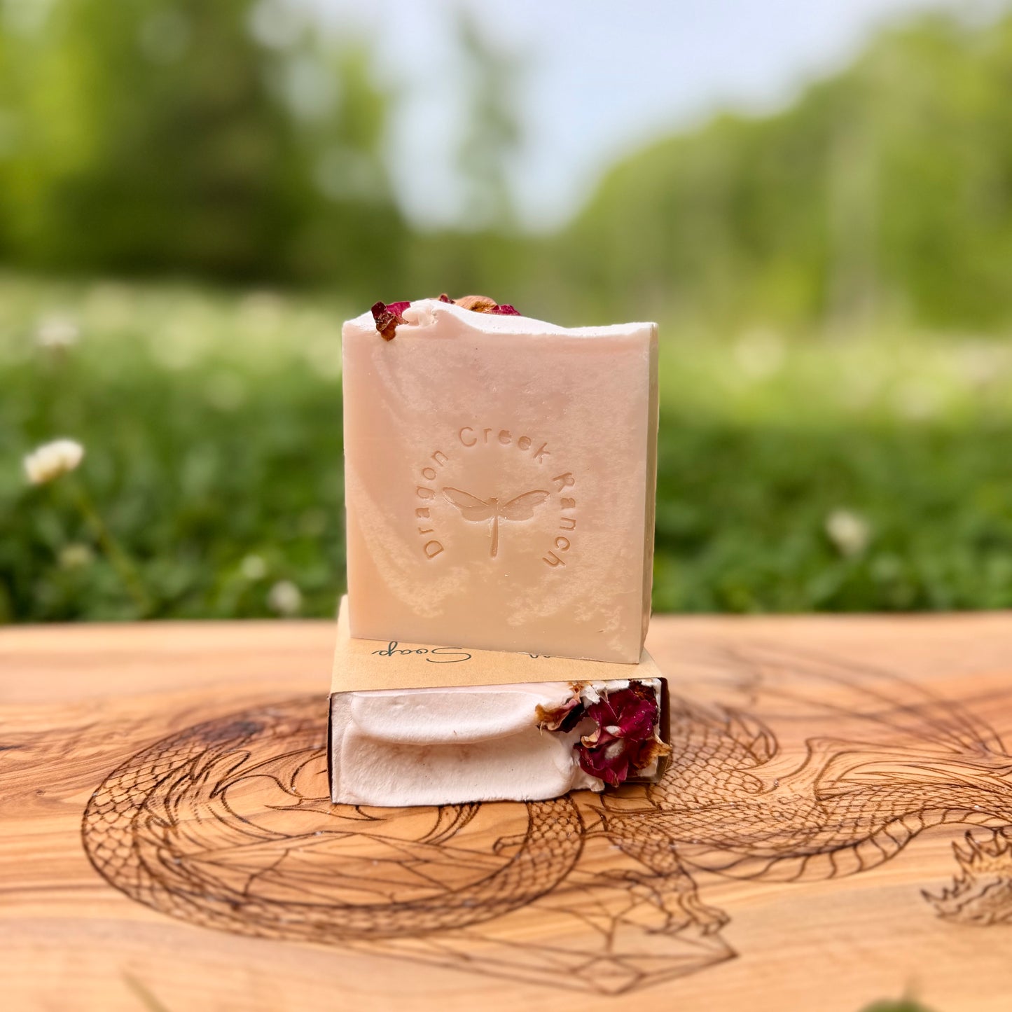 Bar of soap with dried flowers on a wooden stand against a natural background