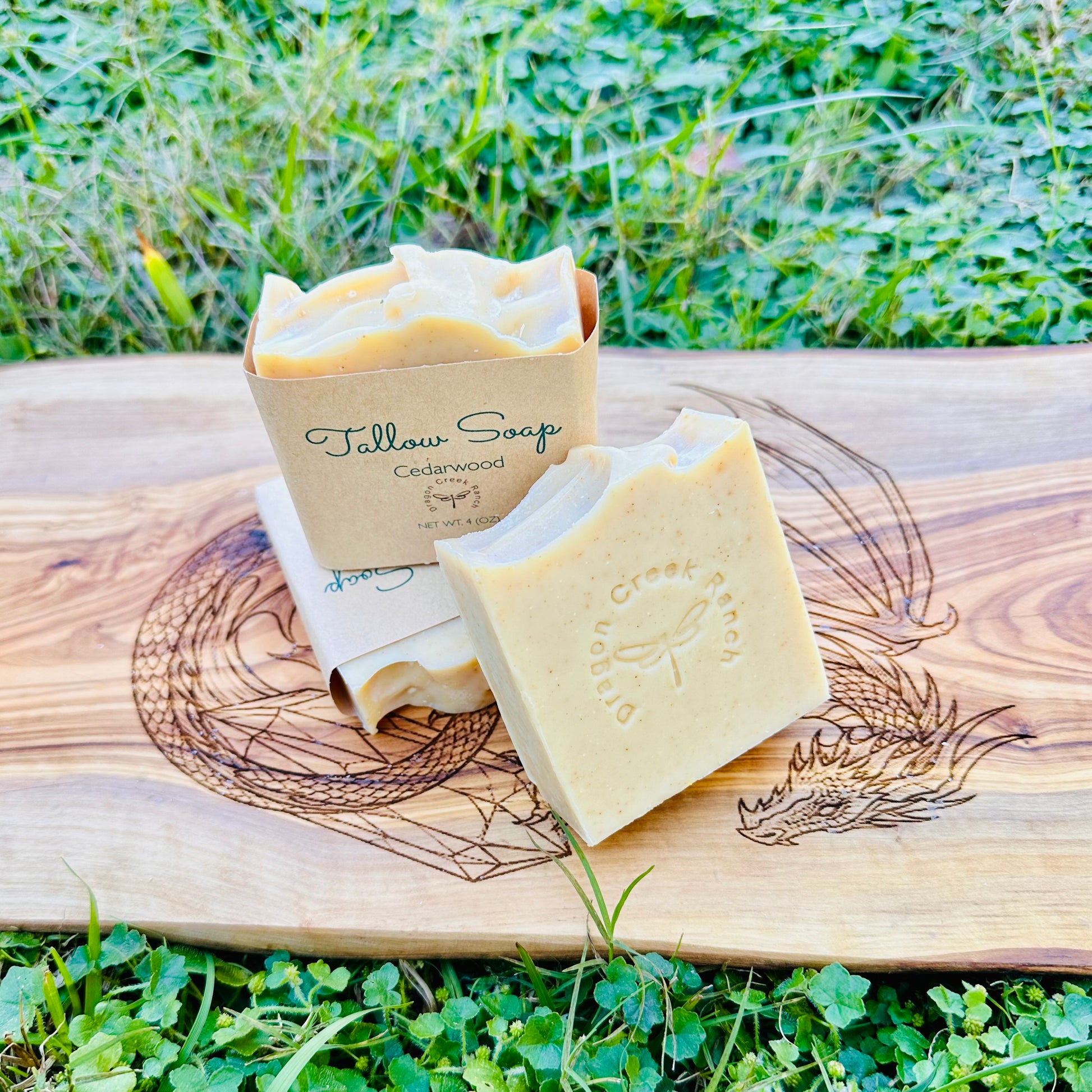 Tallow Soap bar and packaging on a wooden board with grass in the background