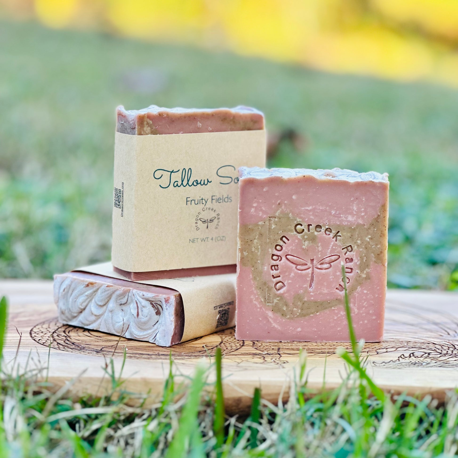 Three bars of pink and green colored soap on a wooden block with a natural background