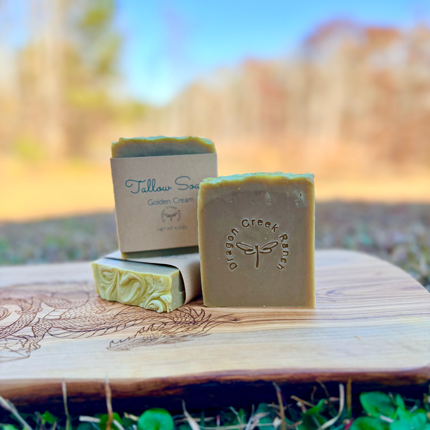 Three bars of green colored soap with 'Dragon Creek Ranch' branding on a wooden surface outdoors.