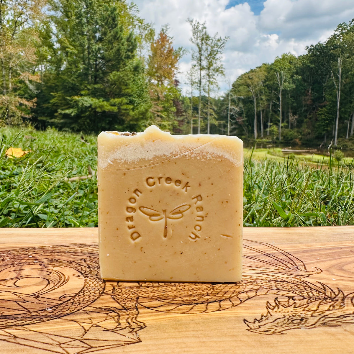 Bar of manuka honey oats and lavender soap with 'Dragon Creek Ranch' branding on a wooden surface with a natural background