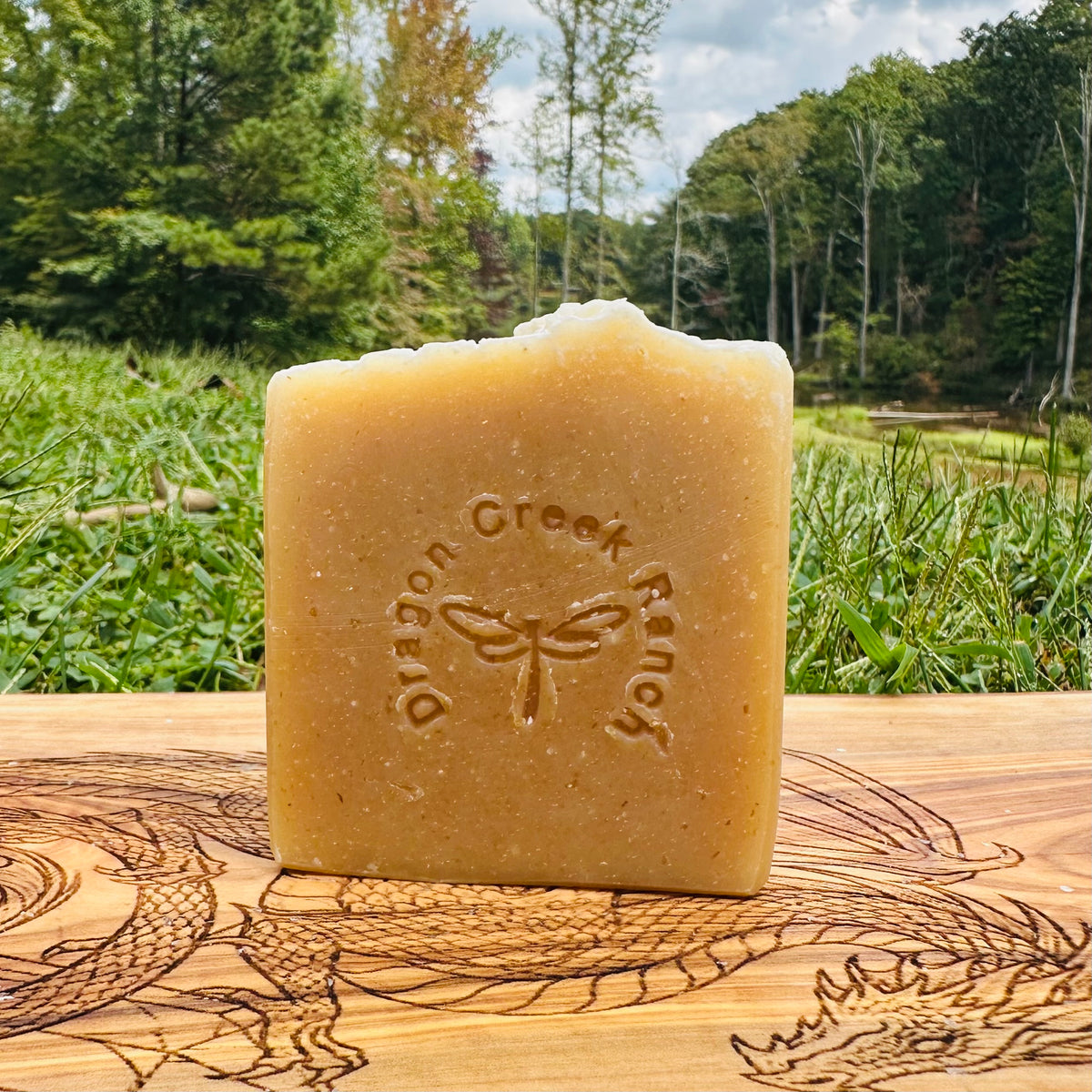 Bar of manuka honey and oats tallow soap with 'Dragon Creek Ranch' branding on a wooden surface with a natural background