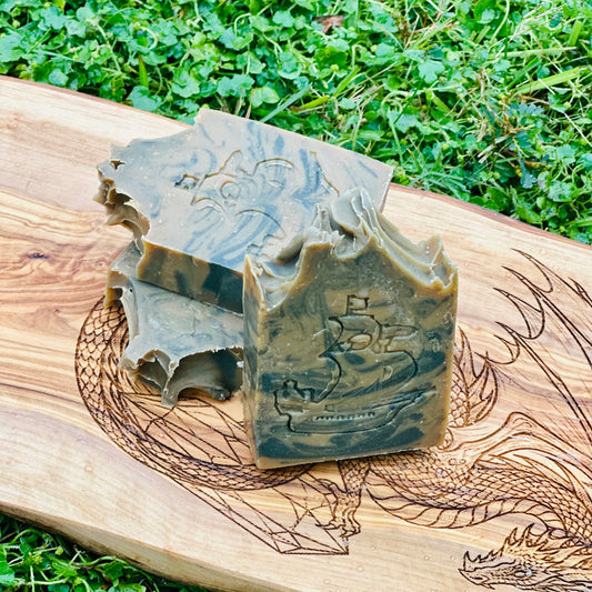 Two pieces of soap with engraved designs on a wooden board outdoors.