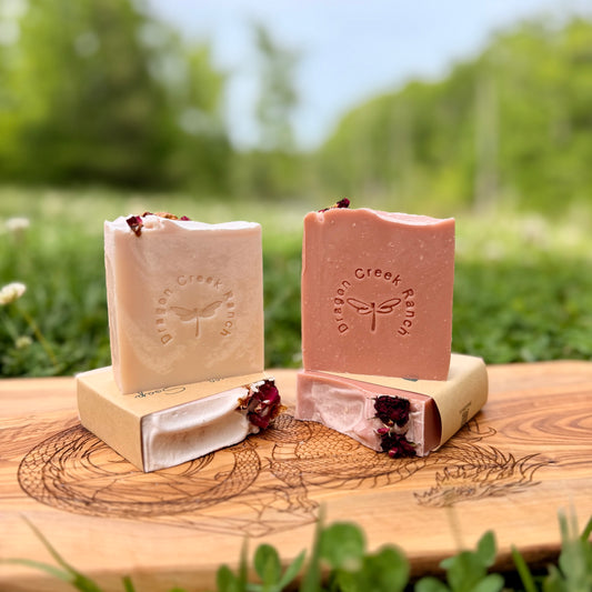 Four bars of pink colored soap on a wooden board with a natural background