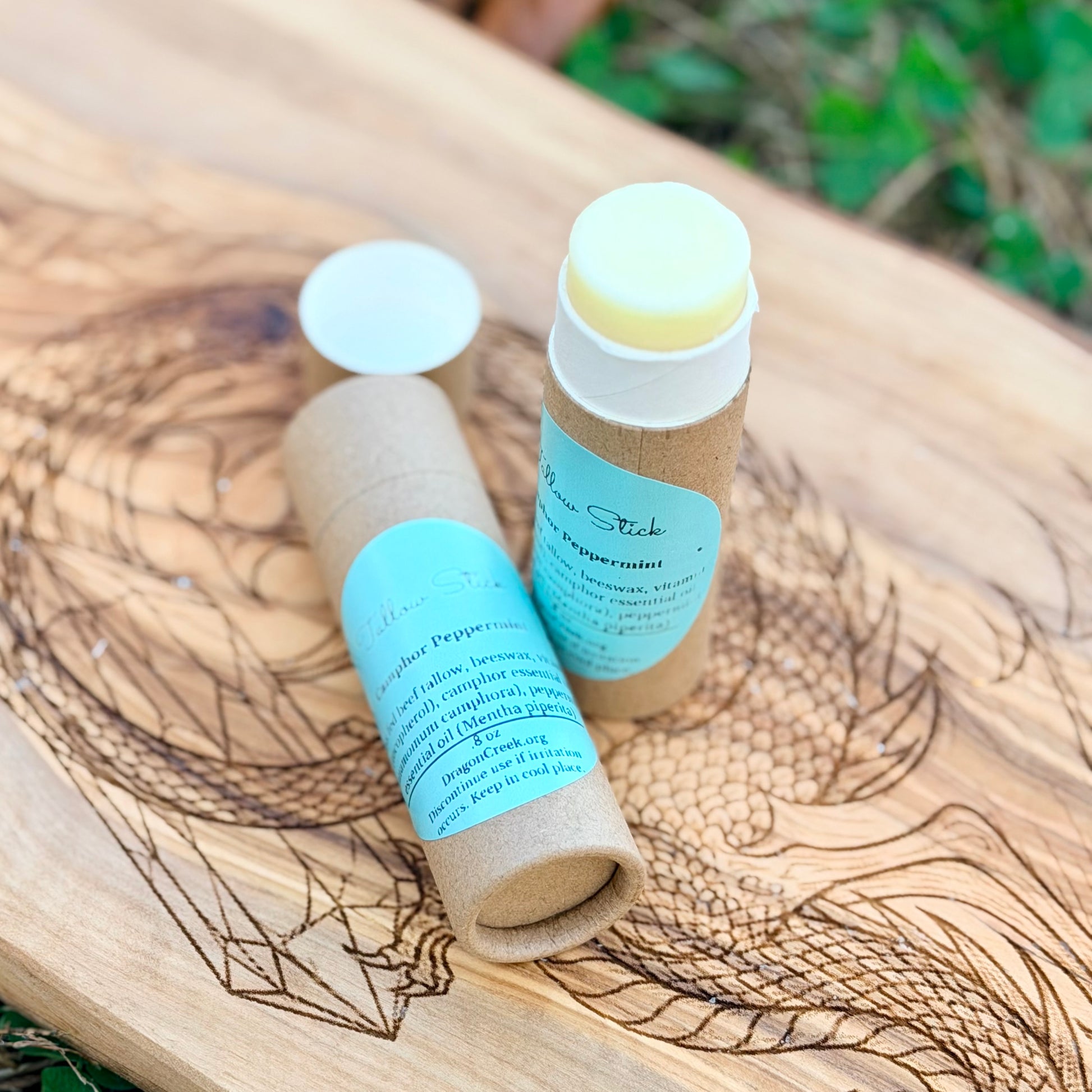 Two lip balm sticks with cardboard tubes on a wooden surface